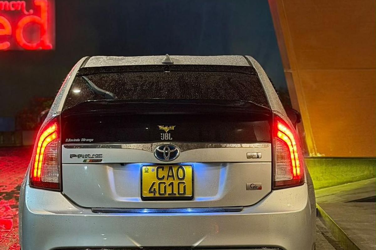 Private hybrid car waiting at night with its lights on