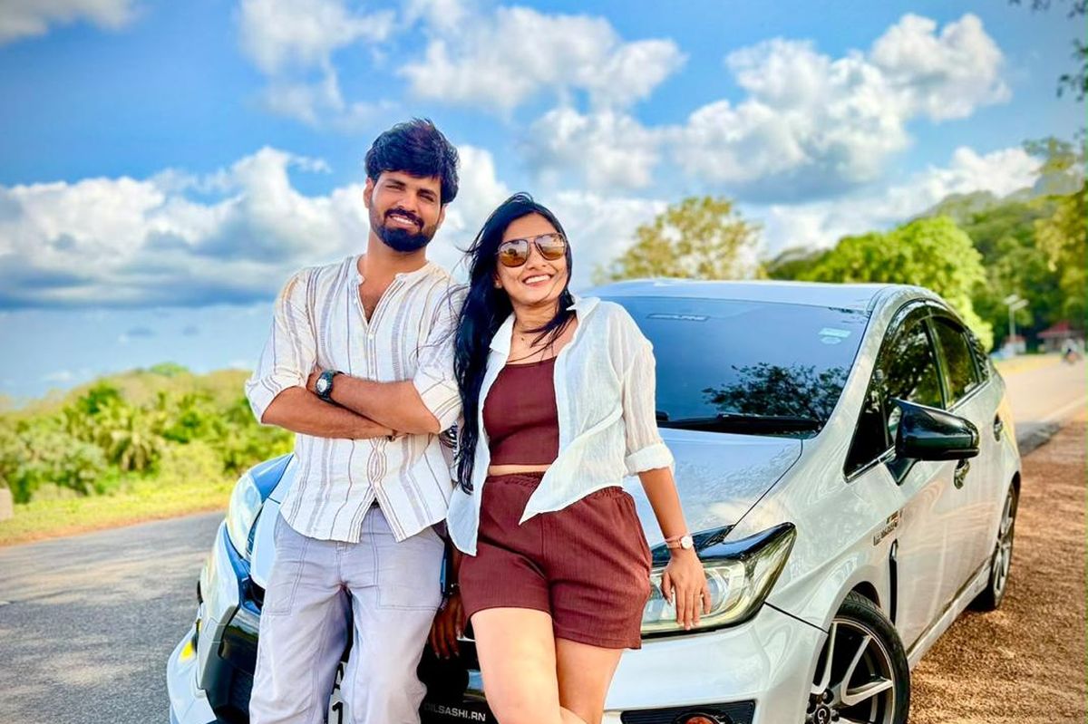 Couple posing beside their private car on a scenic Sri Lankan road
