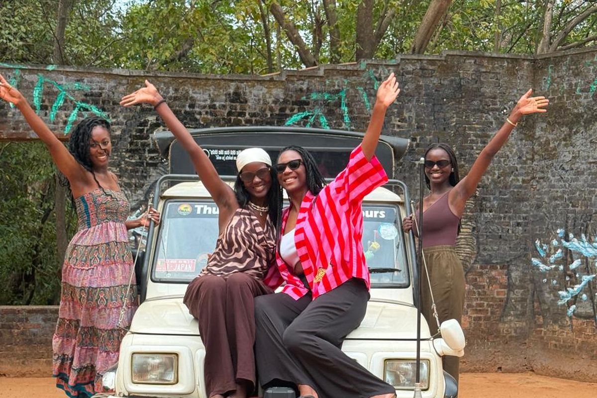 Group of friends cheering with raised arms on their safari jeep