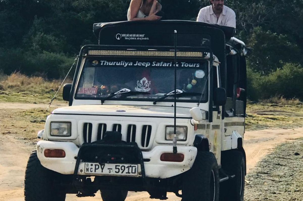 Safari jeep with guests on the roof on a sandy national park track