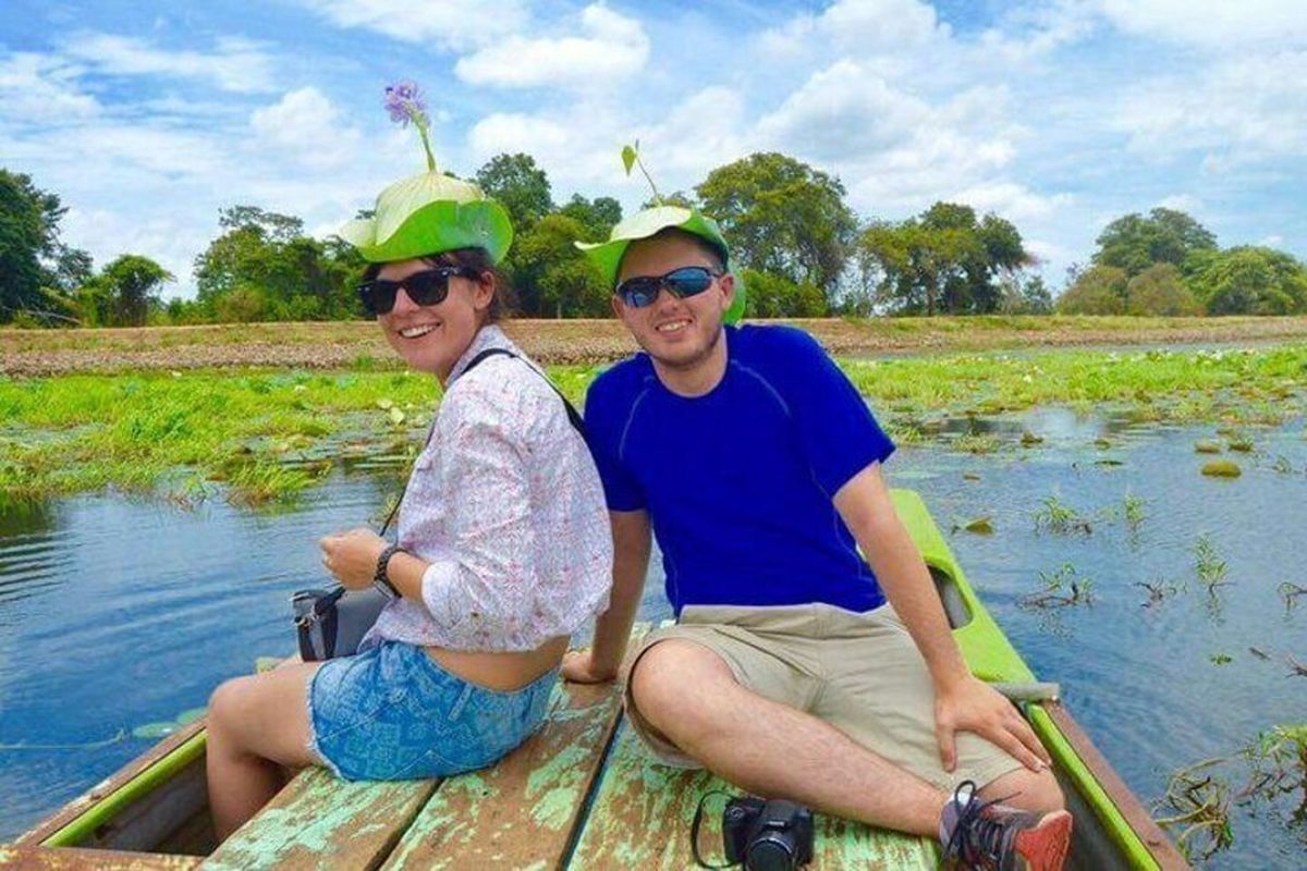 Two guests in leaf hats on a boat among lotus plants