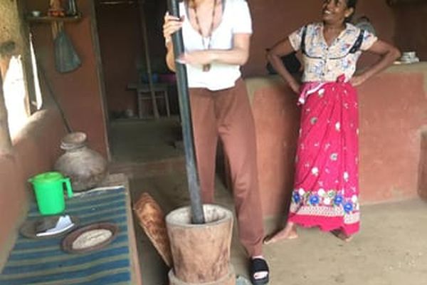 Guest pounding rice with a wooden mortar beside a village woman